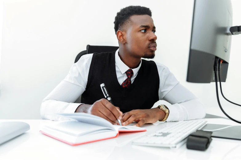 a man sitting at a desk in front of a computer, pen and paper, man is with black skin, wearing a shirt with a tie, thumbnail