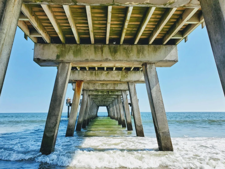 the underside of a pier over a body of water, sunny day at beach, instagram post, architecture photo, video