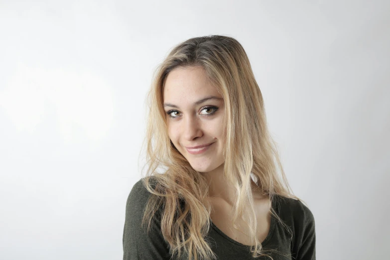 a woman with long blonde hair posing for a picture, a character portrait, pexels contest winner, in front of white back drop, slight nerdy smile, alexandre bourlet, uploaded