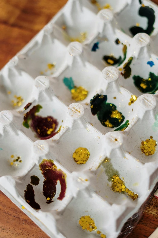 a tray of paint sitting on top of a wooden table, by Colijn de Coter, process art, gemstones and gold, tissue ornament, eggs, thumbnail