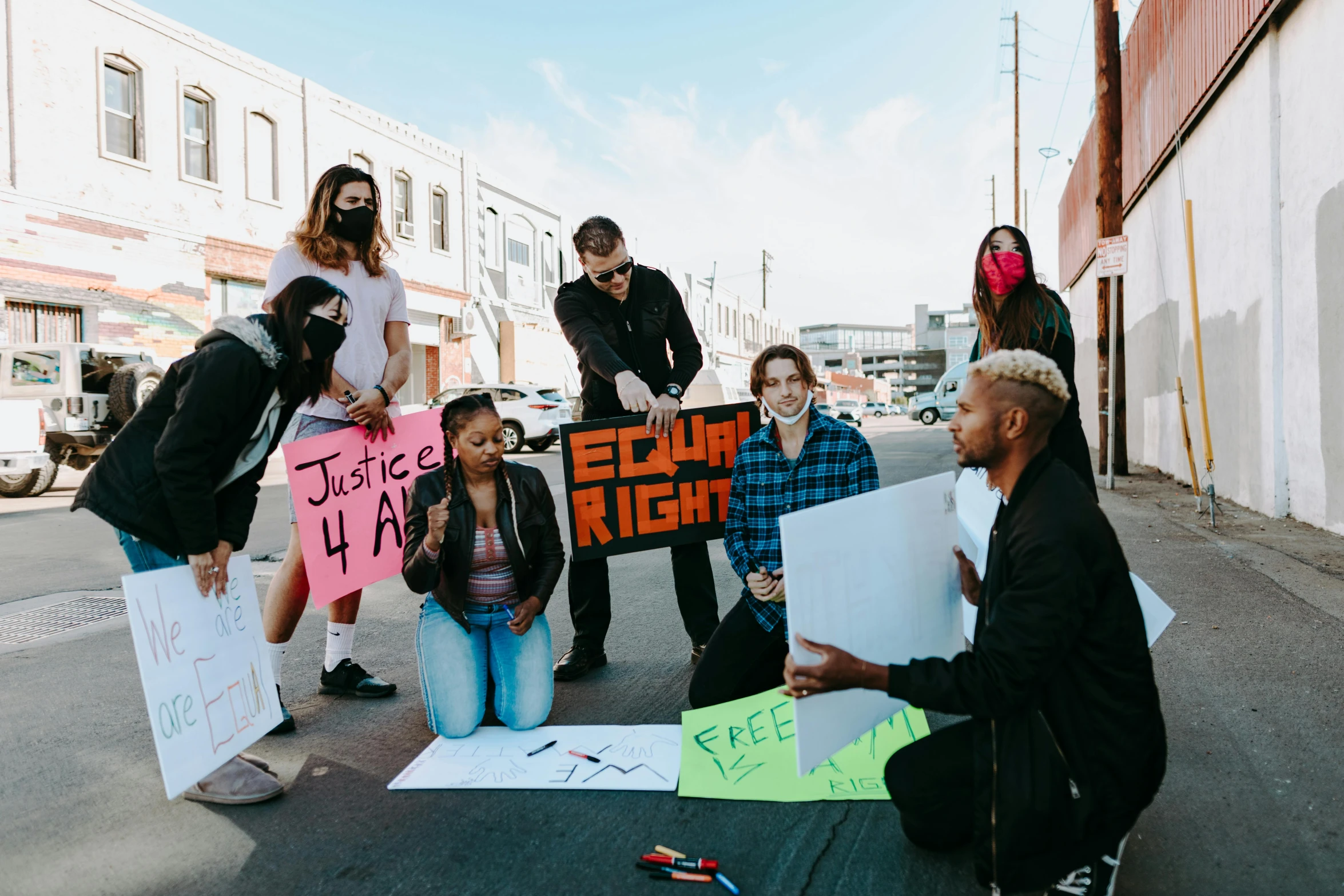 a group of people sitting on the ground holding signs, by Julia Pishtar, pexels contest winner, black arts movement, standing on street corner, group sit at table, brittney lee, hollywood standard