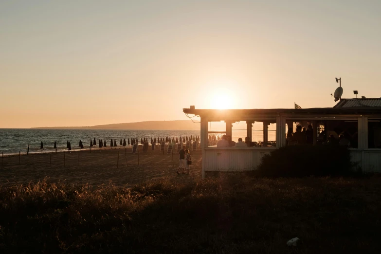 a group of people standing on top of a sandy beach, during a sunset, profile image, beach bar, jovana rikalo