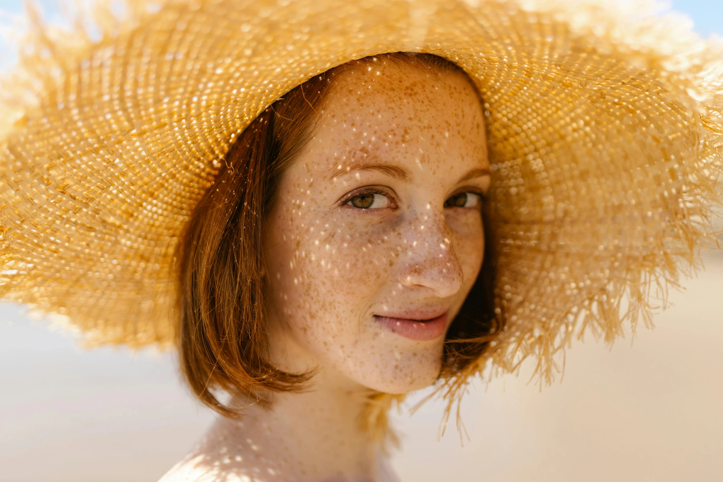 a woman wearing a straw hat on the beach, a portrait, pexels contest winner, renaissance, rosy cheeks with freckles, halo over her head, cinnamon skin color, shimmer detailed