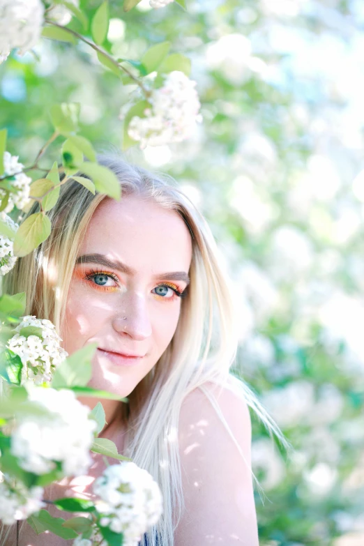 a woman standing next to a tree with white flowers, by Sara Saftleven, pexels contest winner, aestheticism, portrait of kim petras, backlit beautiful face, square, dslr photo of a pretty teen girl