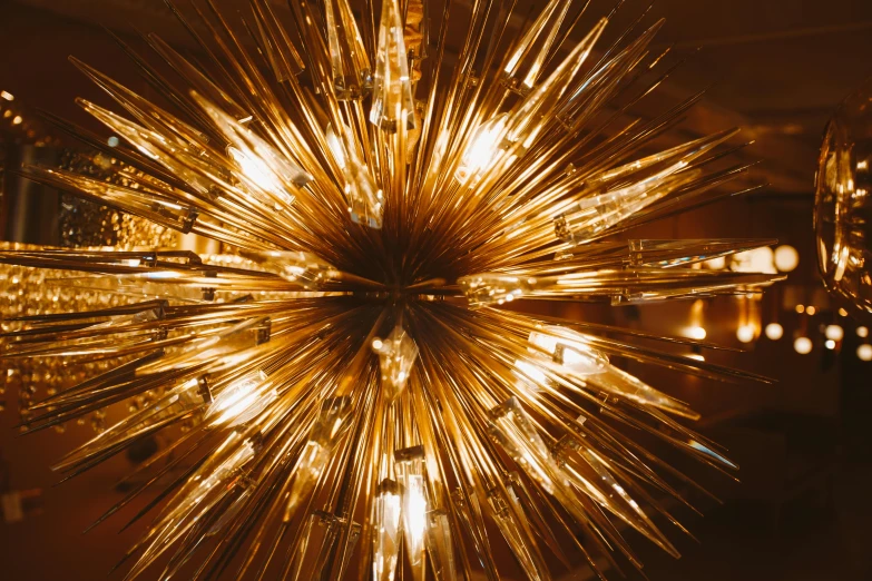 a close up of a chandelier with lights in the background, inspired by Bruce Munro, pexels contest winner, large electrical gold sparks, viewed from above, starburst, brown