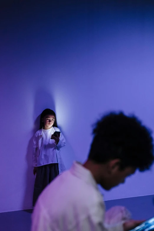 a couple of people that are standing in a room, a hologram, by Jang Seung-eop, trending on unsplash, interactive art, tiny girl looking on, purple light, shot on iphone 6, worried