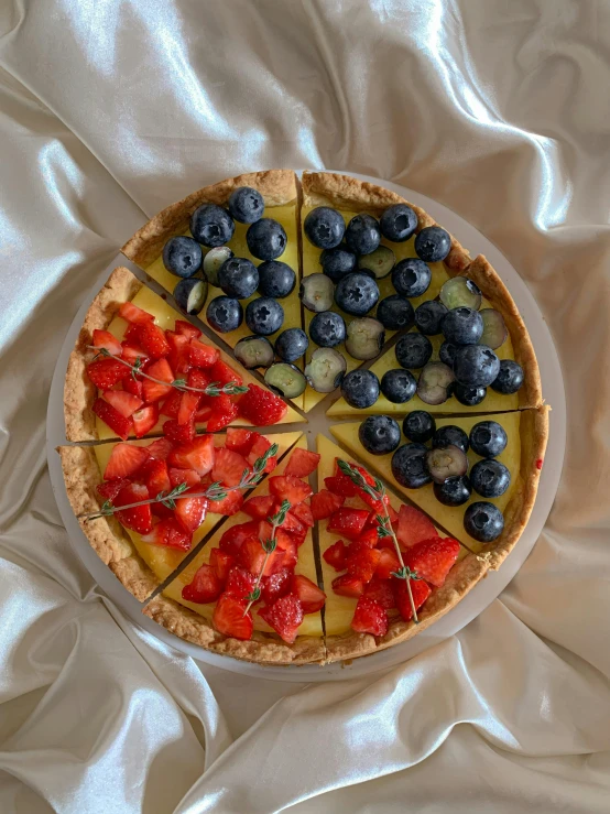 a pie sitting on top of a bed covered in white sheets, a pastel, inspired by François Louis Thomas Francia, unsplash, made of flowers and berries, 6 pack, patriotic!, frontal shot