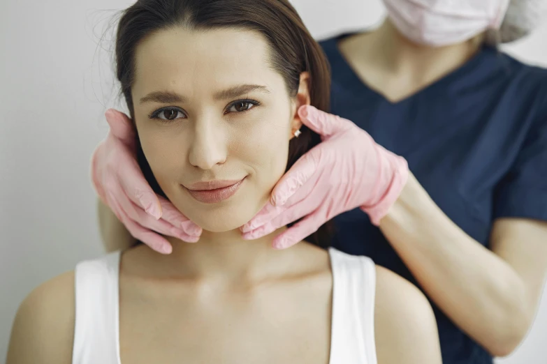 a woman getting her face examined by a doctor, unsplash, renaissance, hand on her chin, square jaw-line, manuka, woman holding another woman