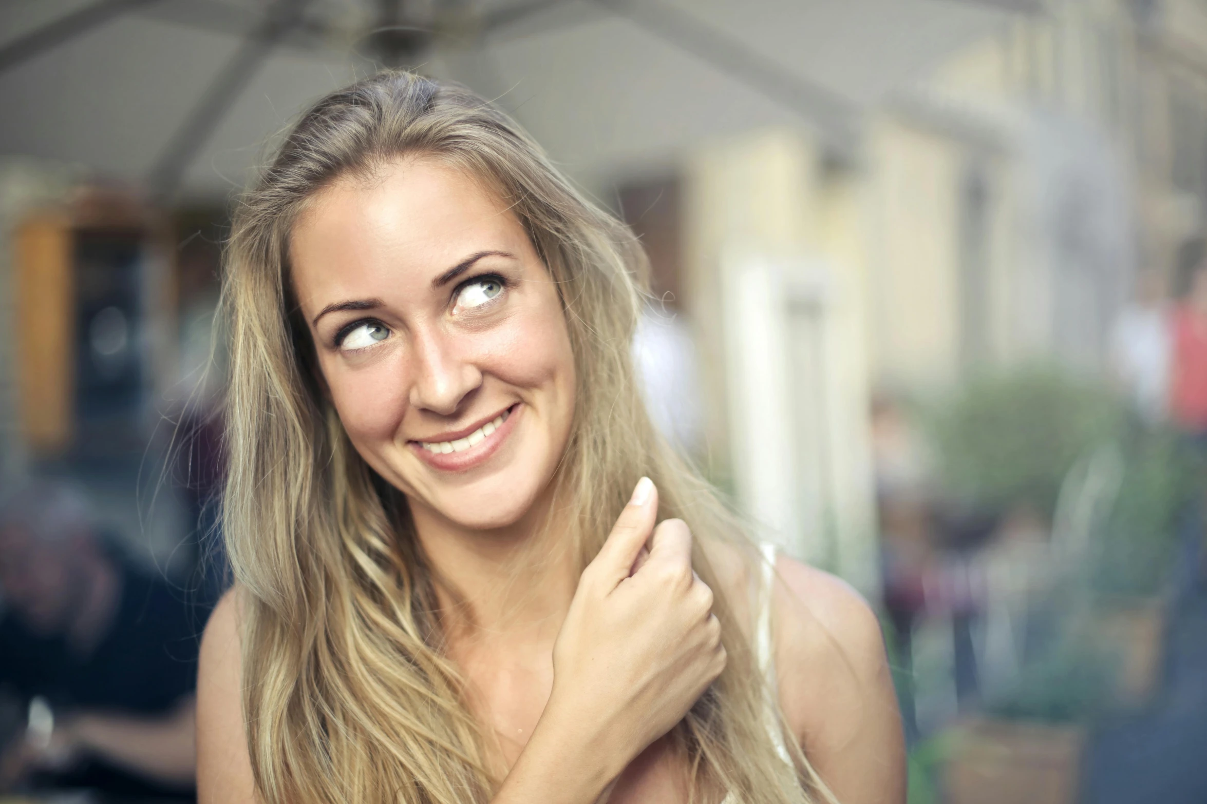 a woman with long blonde hair smiling at the camera, pexels contest winner, happening, looking across the shoulder, looking up at camera, european woman photograph, mischievous grin