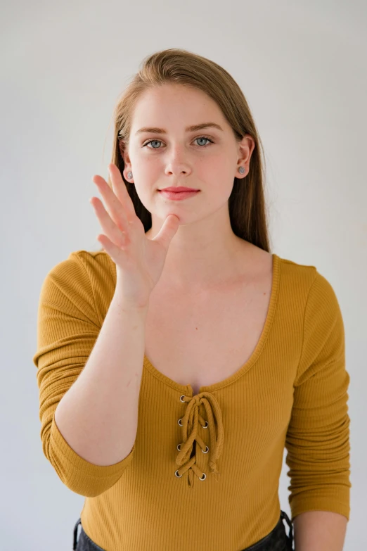 a woman making a stop sign with her hands, trending on pexels, renaissance, acting headshot, soft pale golden skin, wearing a cute top, wearing a yellow dress