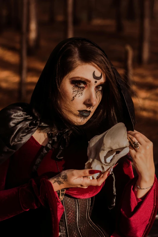 a woman dressed as a witch holding a skull, an album cover, pexels contest winner, wearing cultist red robe, l critical role, look, deity)