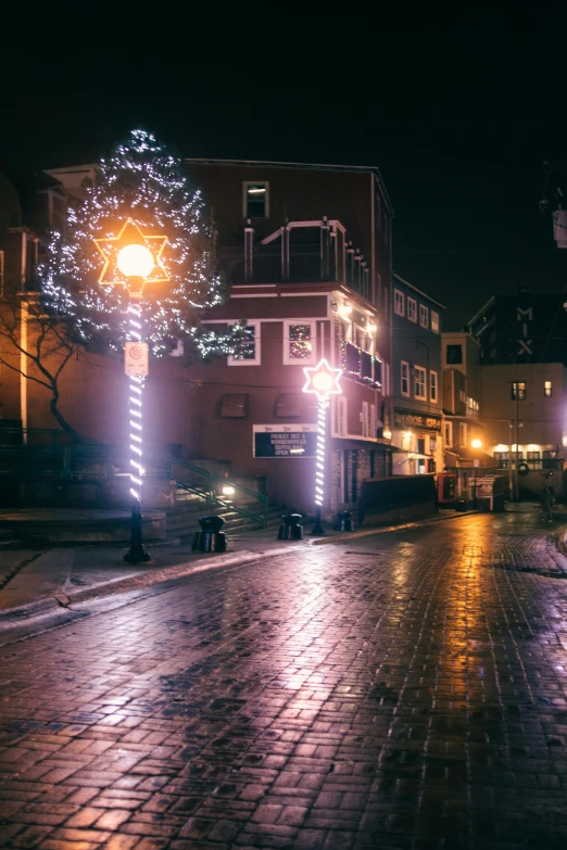 a cobblestone street is lit up with christmas lights, by Julia Pishtar, low - light photograph, quebec, ground level view of soviet town, gif