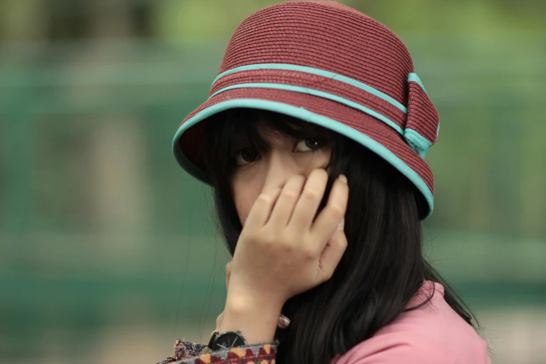 a woman with a hat covering her face, by Basuki Abdullah, pixabay, hurufiyya, maroon, square, young asian girl, retro colour