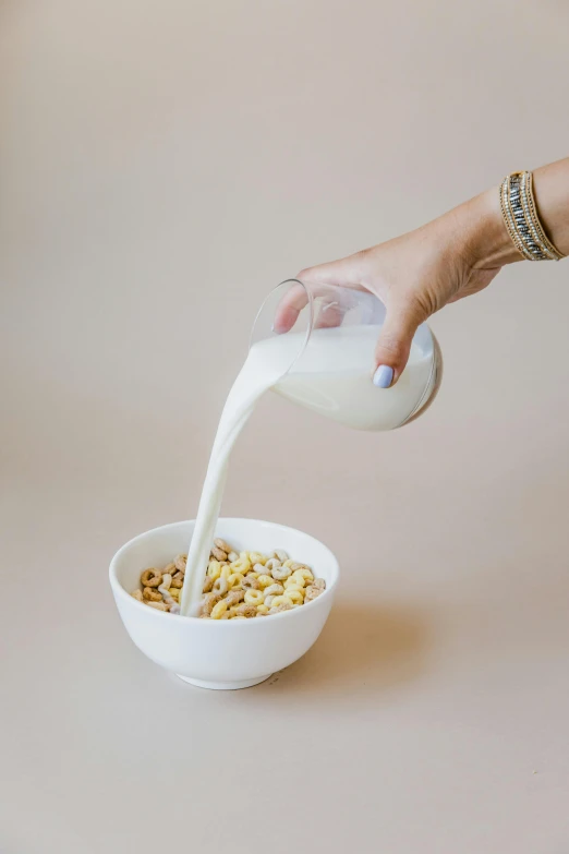a person pouring milk into a bowl of cereal, by Jessie Algie, smooth porcelain skin, vanilla, designer product, silo