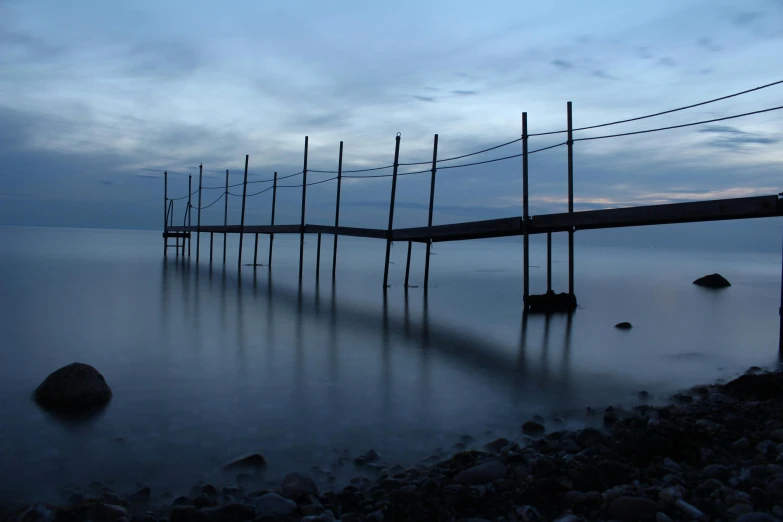a long dock in the middle of a body of water, a picture, inspired by Jan Rustem, unsplash, blue hour, 2 5 6 x 2 5 6 pixels, hammershøi, rope bridges