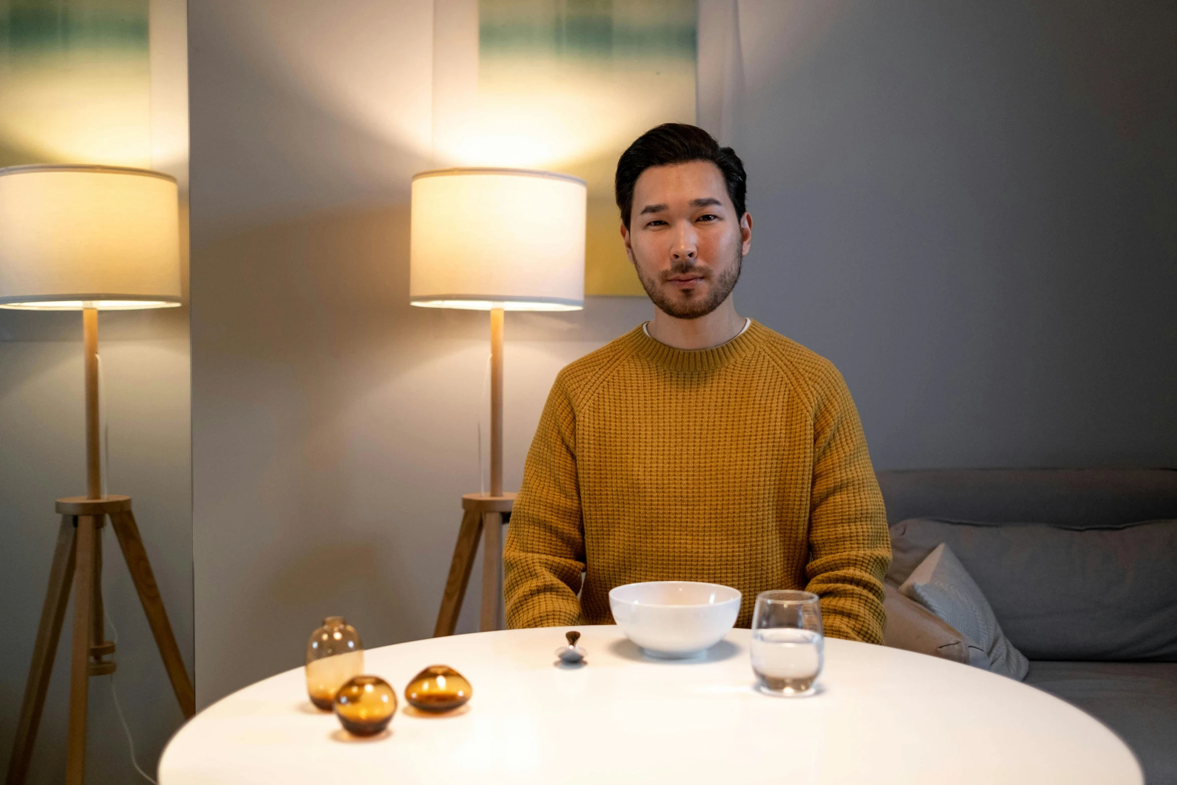 a man sitting at a table with a bowl of food, a portrait, unsplash, shin hanga, he is wearing a brown sweater, holding a candle holder, lachlan bailey, kintsugi