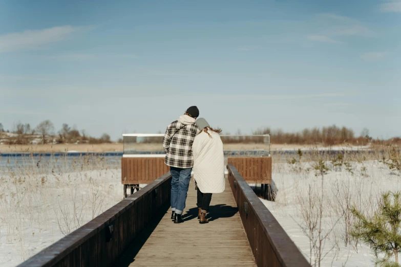 a man and a woman walking across a wooden bridge, trending on unsplash, happening, winter lake setting, hugging, background image, ground - level medium shot