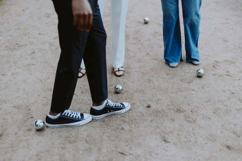 a group of people standing on top of a dirt field, bowling, white shoes, top selection on unsplash, grey pants and black dress shoes