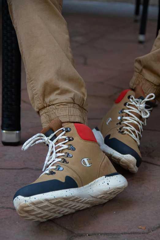 a close up of a person's shoes on a sidewalk, inspired by Salomon van Abbé, khakis, champion, wearing boots, red + black + dark blue + beige