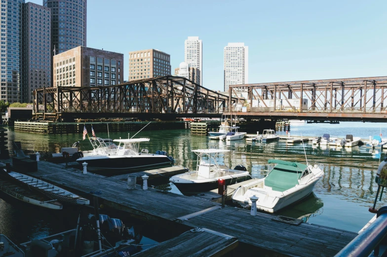 a number of boats in a body of water near a bridge, a photo, by Robbie Trevino, hurufiyya, chicago, small port village, sunny day time, ignant