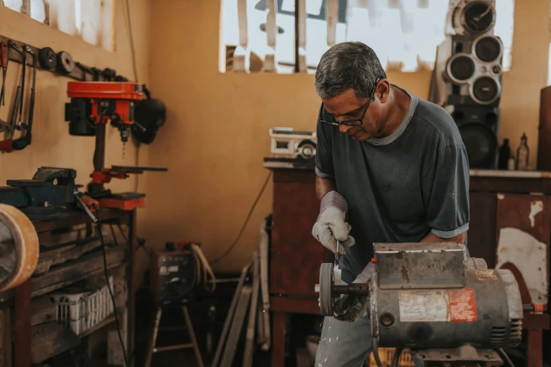 a man working on a machine in a workshop, pexels contest winner, fan favorite, avatar image, chilean, saws