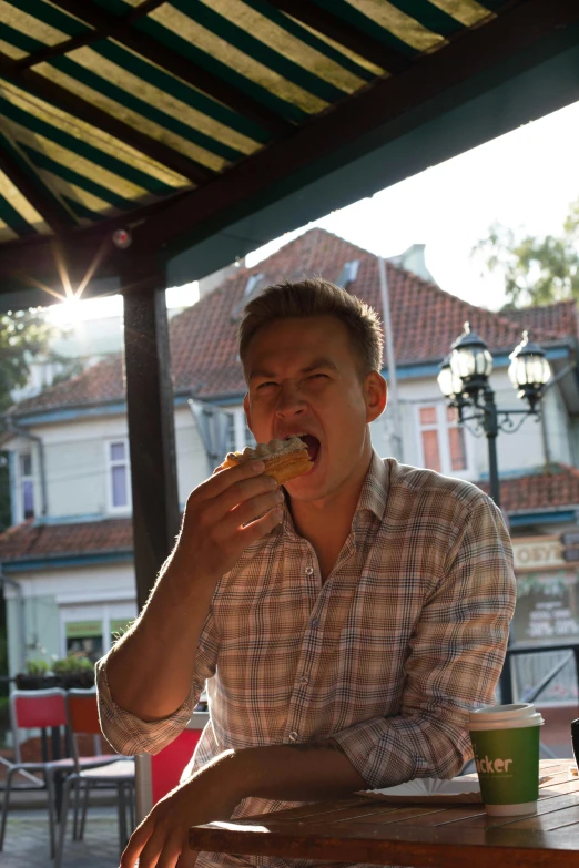 a man sitting at a table eating food, blonde guy, bosnian, with mouth open, during golden hour