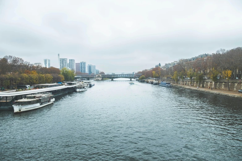 a river filled with lots of boats next to tall buildings, a photo, pexels contest winner, visual art, portrait of paris, overcast gray skies, fall season, a small