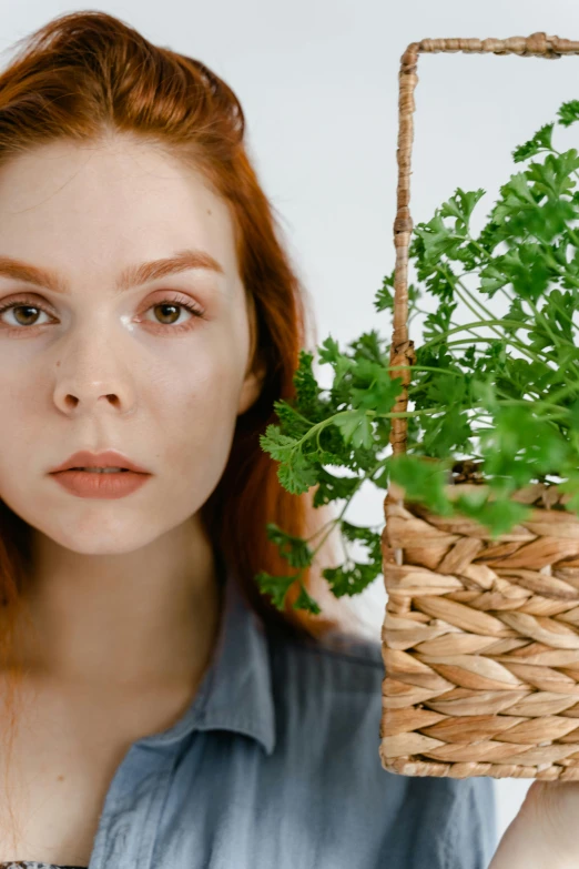 a woman holding a basket with a plant in it, a character portrait, trending on pexels, hyperrealism, she is redhead, close-up perfect face, herbs, pouty face