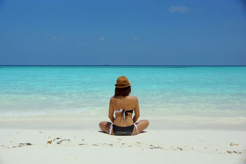 a woman sitting on top of a beach next to the ocean, avatar image, white sandy beach, profile image, facing away