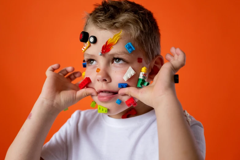 a young boy with legos on his face, inspired by Damien Hirst, pexels contest winner, photoshoot for skincare brand, orange head, avatar image