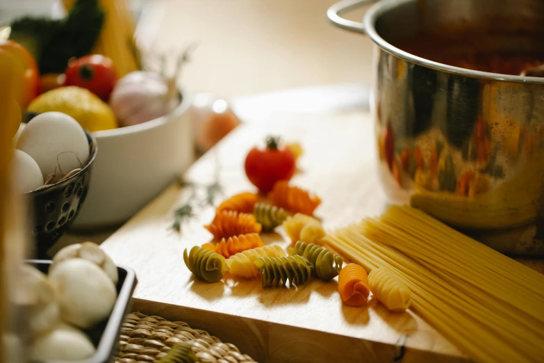 a wooden cutting board topped with pasta and vegetables, a still life, pexels contest winner, pots and pans, background image, evening light, up close shot