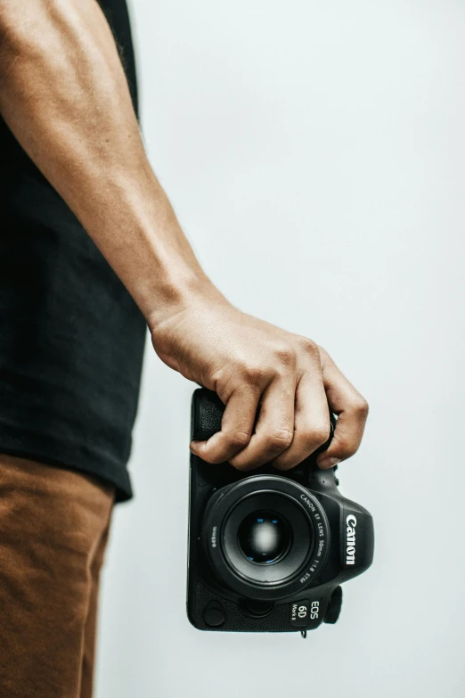 a man holding a camera in his hand, body and headshot, unsplash photo contest winner, plain background, club photography