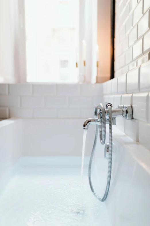 a bath tub filled with water next to a window, by Andries Stock, unsplash, dwell, piping, close-up photograph, short spout