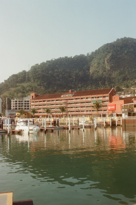a body of water with a mountain in the background, hotel, docked at harbor, early 2 0 0 0 s, bizzaro