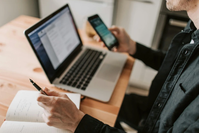 a man sitting at a table with a laptop and a cell phone, by Carey Morris, trending on pexels, avatar image, 1 2 9 7, writing a letter, technical