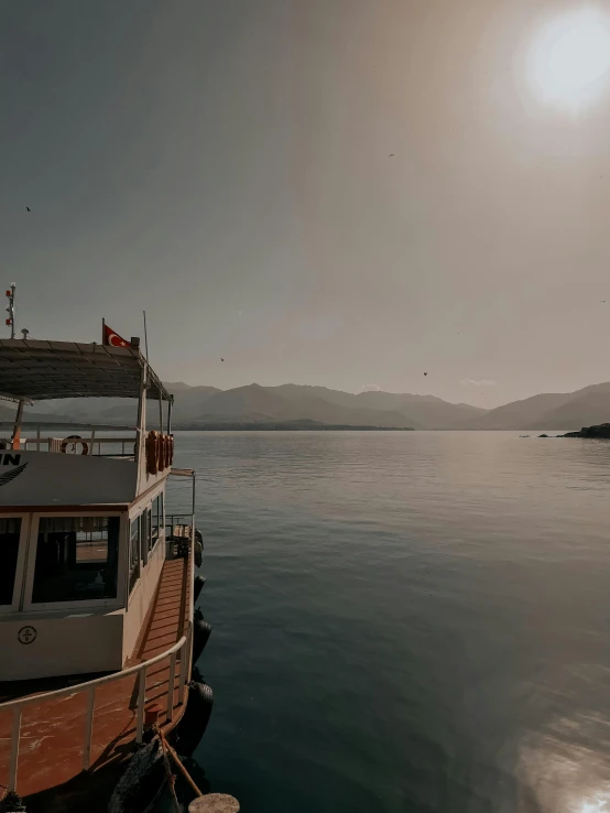 a boat sitting on top of a body of water, happening, mountains and ocean, smokey atmosphere, near a jetty, boka