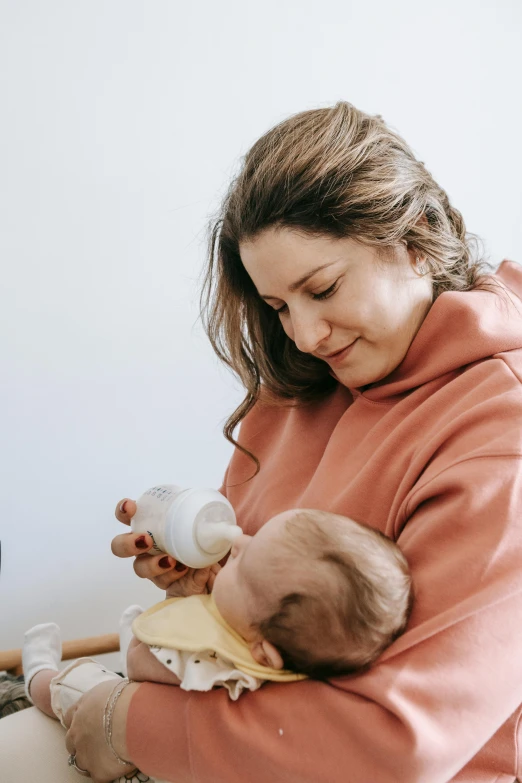 a woman feeding a baby with a bottle, pexels contest winner, white background, manuka, brunette, future tech