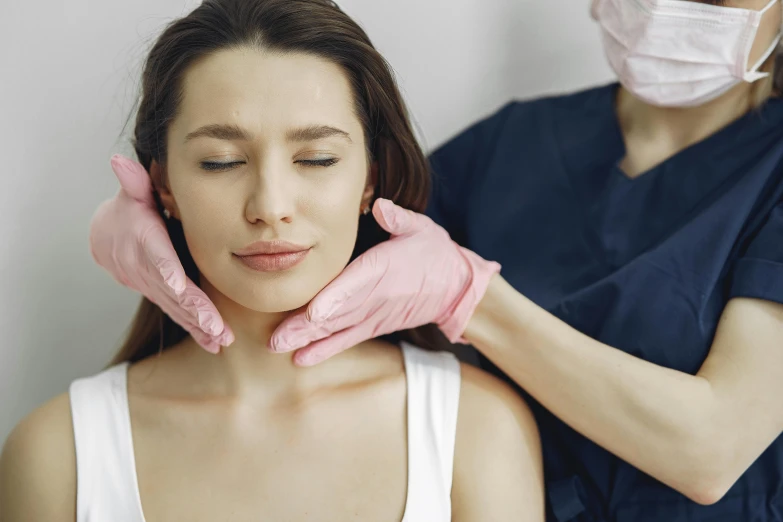 a woman getting her face examined by a doctor, a photo, by Emma Andijewska, trending on pexels, aestheticism, square jaw-line, muscular neck, manuka, larynx