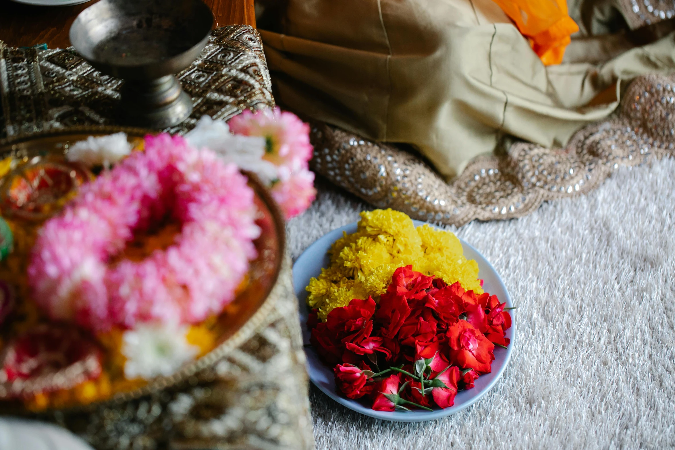 a bowl of flowers sitting on top of a table, hurufiyya, yellow carpeted, red and gold cloth, bed of flowers on floor, offering a plate of food