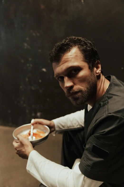 a man sitting down eating a bowl of food, inspired by Leonid Pasternak, renaissance, henry cavill as james bond, dark backdrop, h3h3, performance