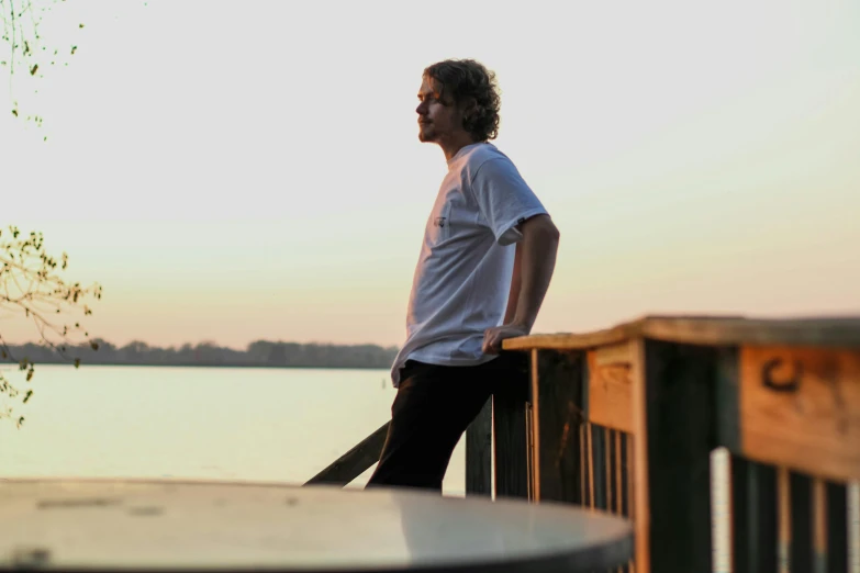 a man standing on a dock next to a body of water, a picture, happening, profile image, connor hibbs, portrait image, vapourwave