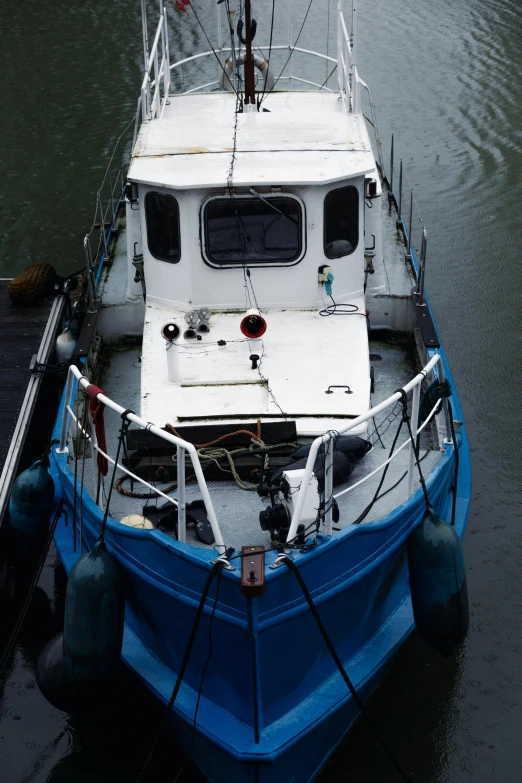 a blue and white boat in a body of water, by Dave Allsop, up close, moored, as photograph, high angle shot