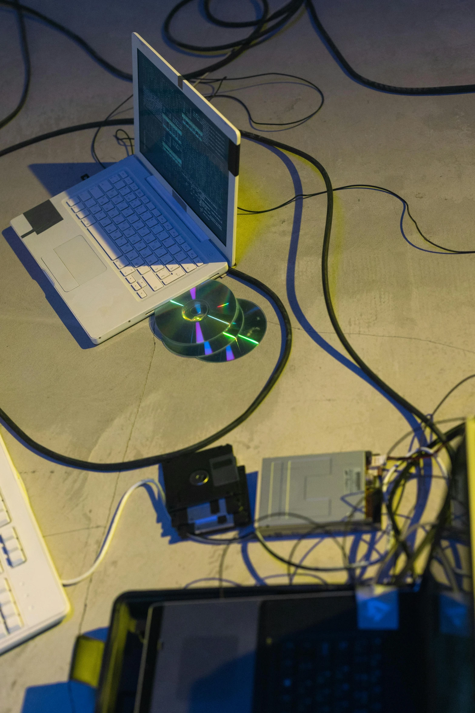 a couple of laptops sitting on top of a table, video art, piles of modular synth cables, blue and yellow lighting, leaked image, a python programmer's despair