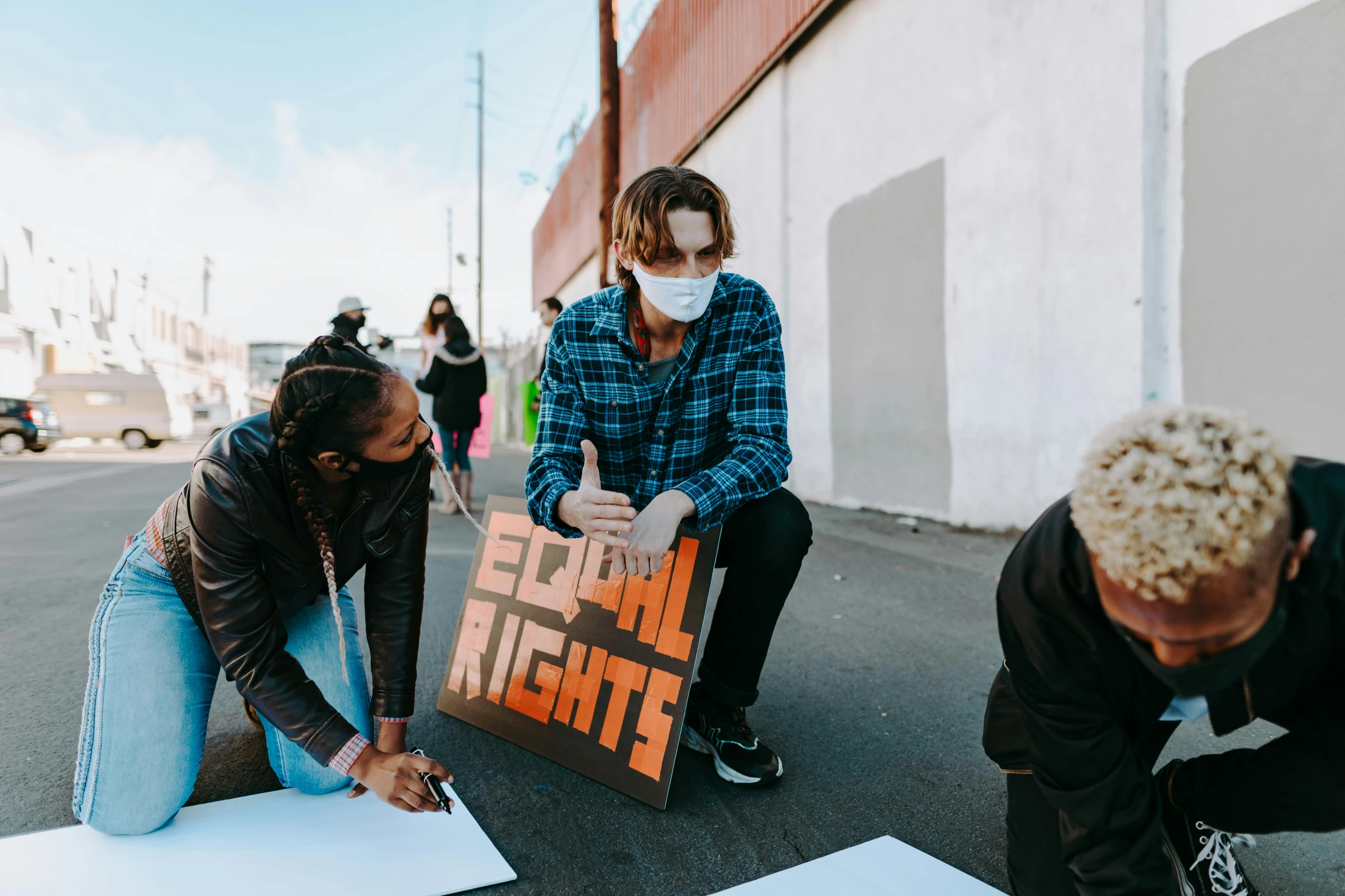 a group of people sitting on the side of a road, by Julia Pishtar, pexels contest winner, graffiti, woman his holding a sign, trans rights, timothee chalamet, signing a bill