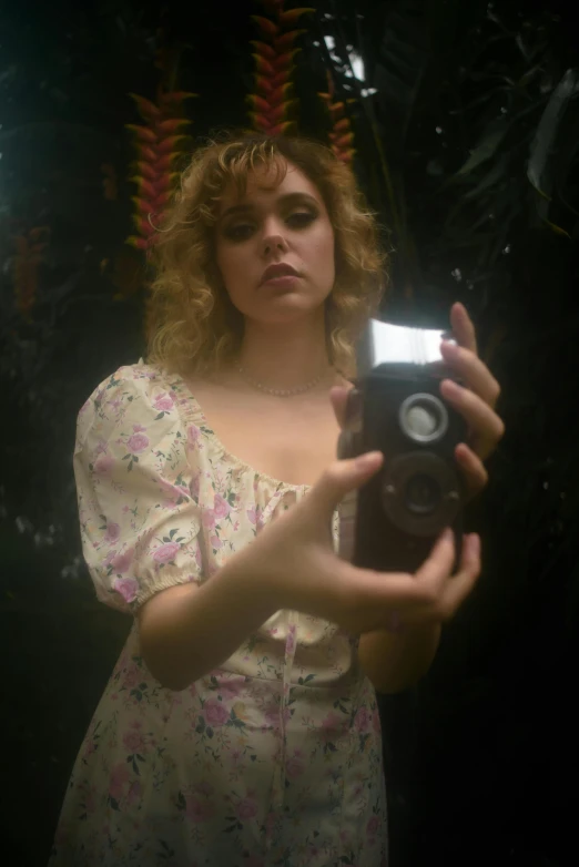 a woman taking a picture of herself in a mirror, an album cover, inspired by Nan Goldin, magic realism, curly blonde hair | d & d, victorian style costume, sophia lillis, (((low light)))