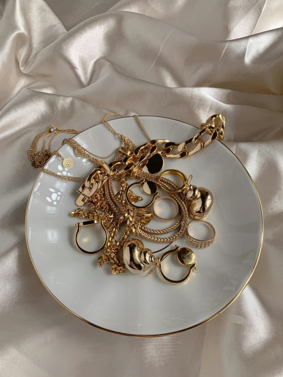 a white plate topped with lots of gold jewelry, by Maggie Hamilton, 1980s photograph, 4k)