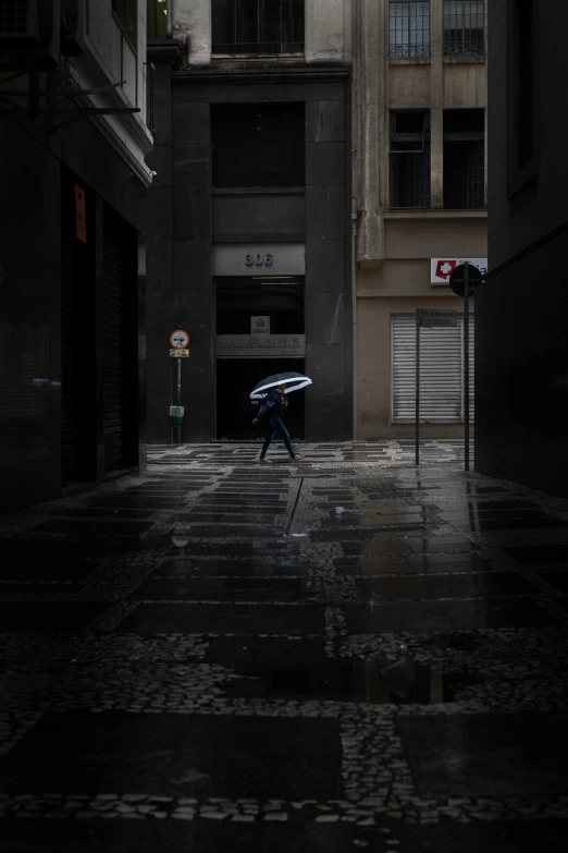 a person walking down a street with an umbrella, by Pedro Pedraja, dark building, paul barson, in a cybercity, fernando guerra