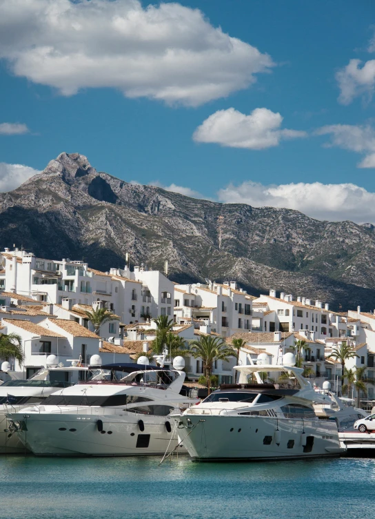 a number of boats in a body of water, by Tom Wänerstrand, pexels contest winner, marbella landscape, white buildings, with mountains as background, square