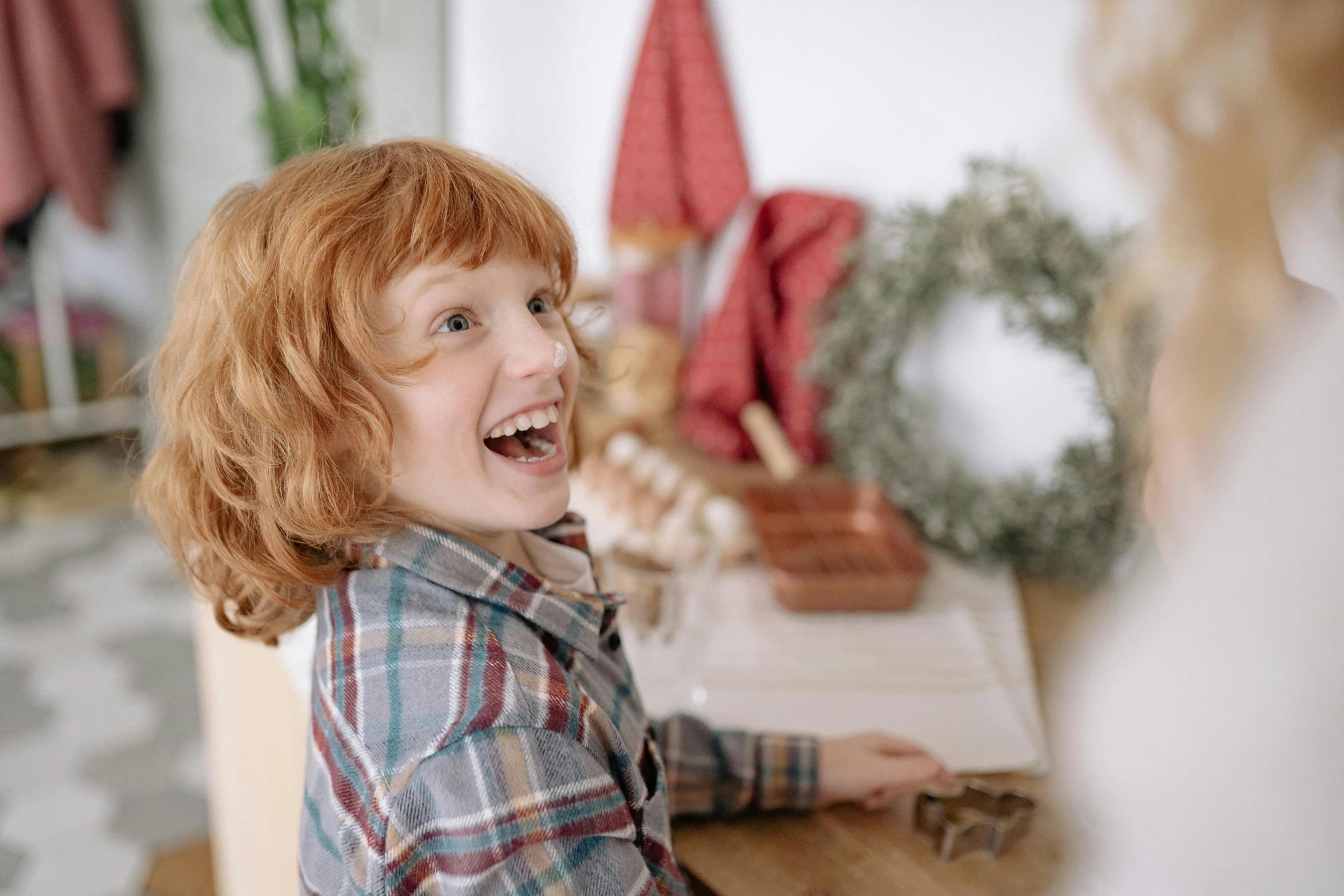 a little girl sitting on top of a wooden table, inspired by Jessie Newbery, pexels contest winner, earing a shirt laughing, red haired teen boy, wearing festive clothing, on a white table