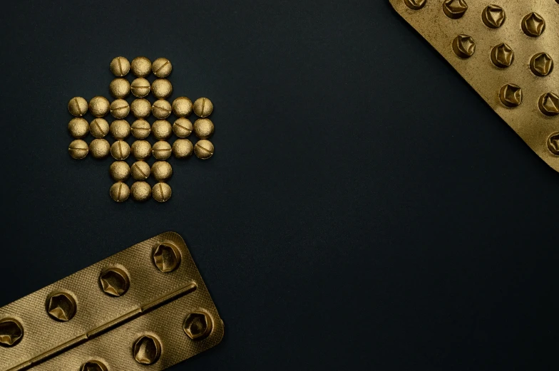 a bunch of pills sitting on top of a table, an album cover, inspired by Joseph Wright of Derby, trending on pexels, digital art, gold and steel intricate, crosses, game board, mathematical interlocking